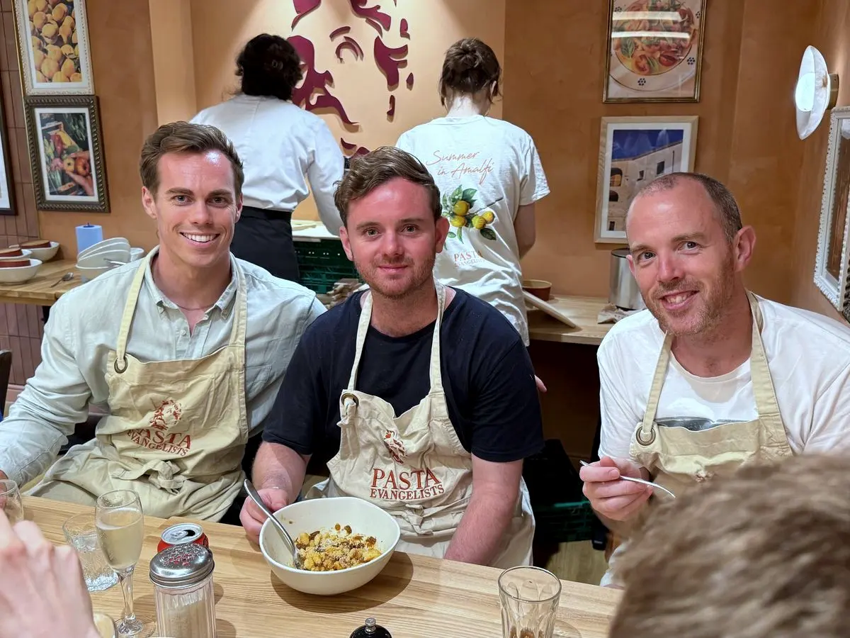 Three teammates in aprons at a pasta-making class